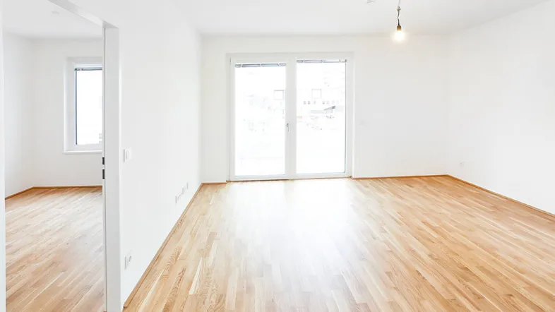 Helles, leeres Zimmer mit Parkettboden und großen Fenstern, bereit zur individuellen Gestaltung.