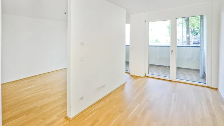 Heller, leerer Raum mit Parkettboden und Zugang zu einem Balkon, ideal für flexible Gestaltung.
