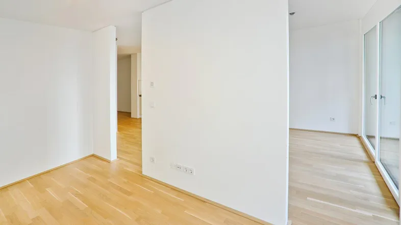 Helles, leeres Zimmer mit Parkettboden und weißen Wänden, bereit zur individuellen Gestaltung.