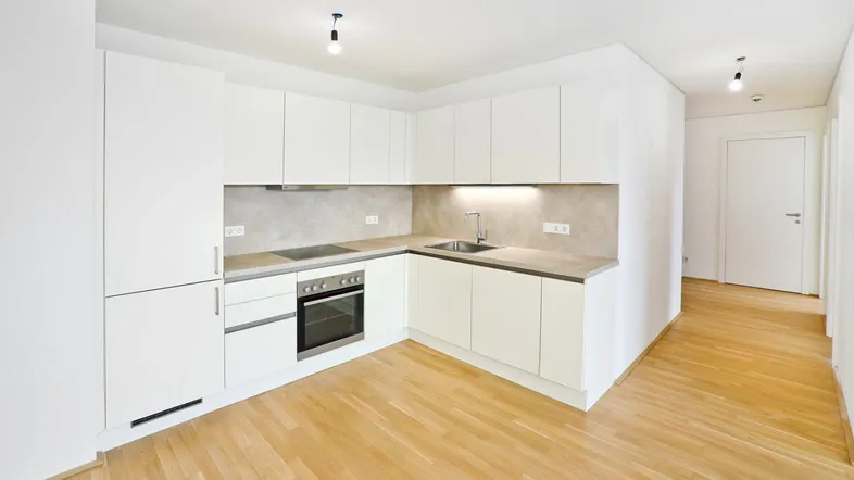 Moderne Einbauküche mit weißen Schränken, integrierten Geräten und hellem Holzfußboden.