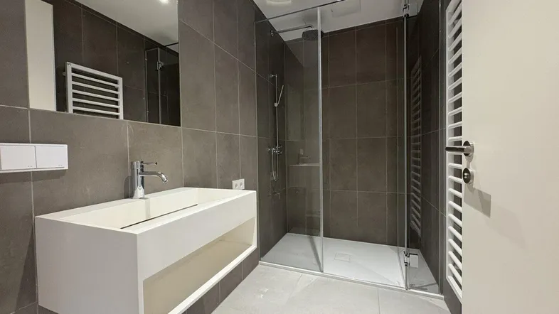 Modernes Badezimmer mit großformatigen Fliesen, schwebendem Waschtisch und begehbarer Dusche.