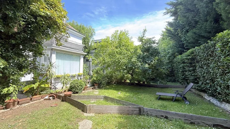 Gepflegter Garten mit Rasenfläche, Bäumen und einer Liege, ideal zum Entspannen im Freien.