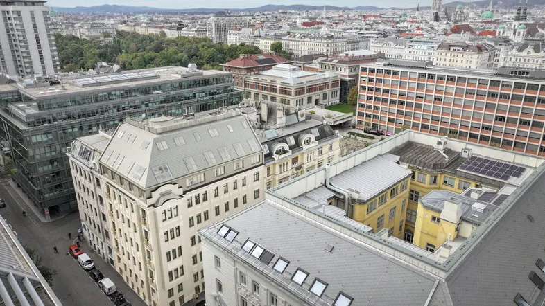 Panoramablick über die Stadt Wien mit historischen und modernen Gebäuden unter bewölktem Himmel.