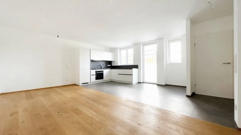 Heller offener Wohn-Essbereich mit moderner Einbauküche und Parkettboden, ideal für modernes Wohnen.