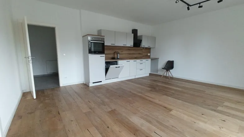 Helles Zimmer mit Holzboden und integrierter Küchenzeile, ideal für offenes Wohnen.
