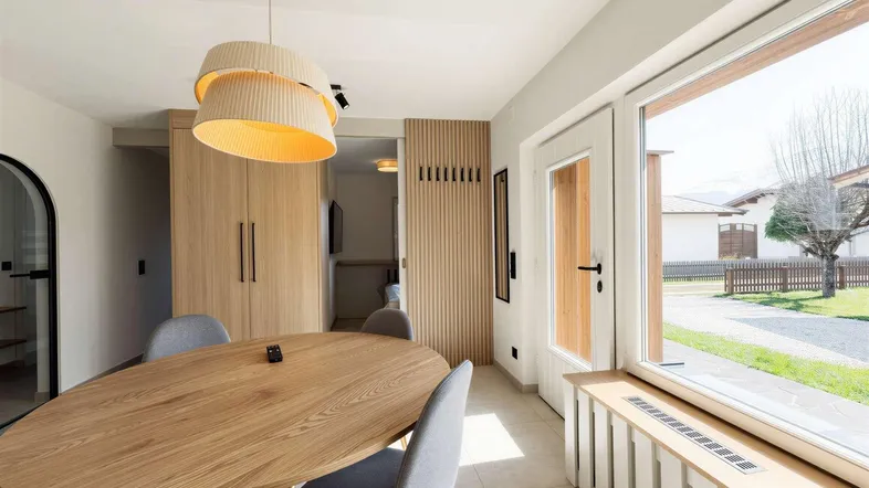Heller Essbereich mit Holztisch, modernen Stühlen und großem Fenster mit Blick ins Grüne.