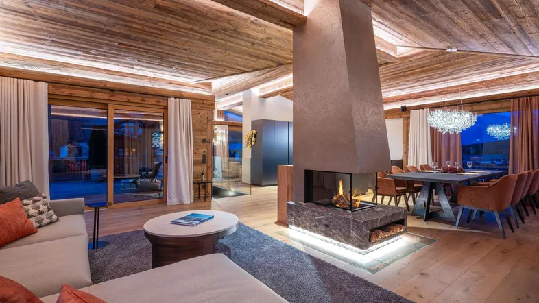 Großzügiger Wohn- und Essbereich mit Holzbalkendecke, modernem Kamin und Zugang zur Terrasse.