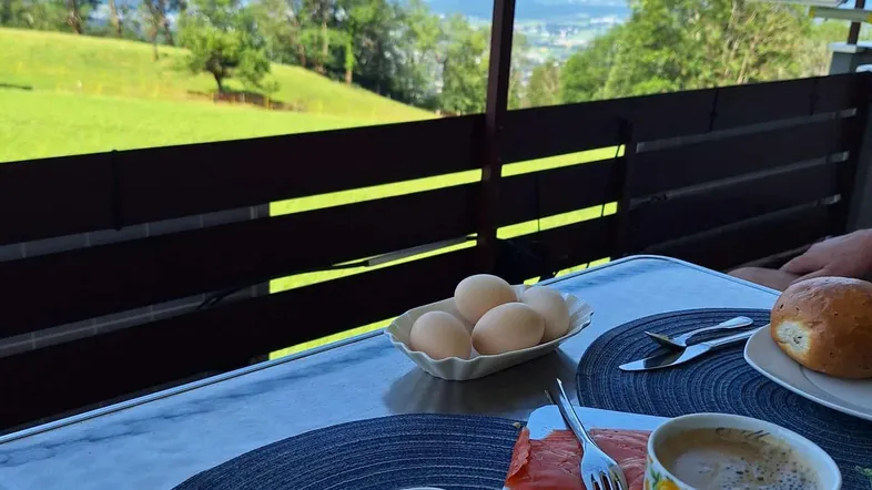 Frühstück auf dem Balkon mit atemberaubendem Blick auf die Berge und grüne Landschaft.