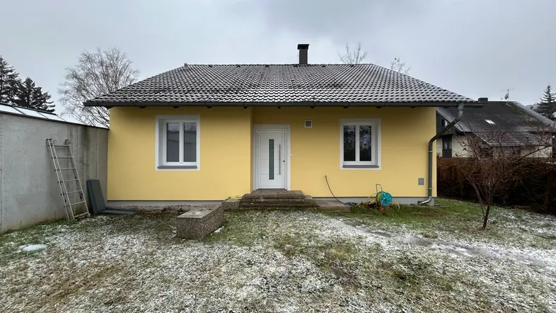 Gelbes Einfamilienhaus mit Satteldach und kleinem Vorgarten im winterlichen Ambiente.