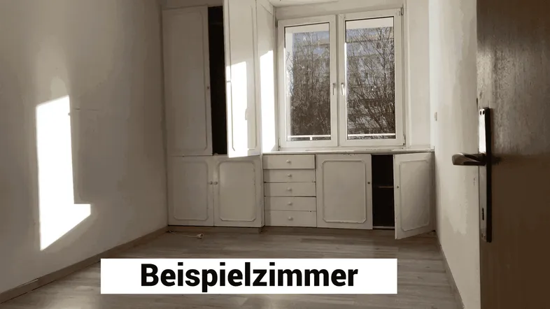 Heller Innenraum mit Laminatboden und eingebauten Schränken unter dem Fenster.