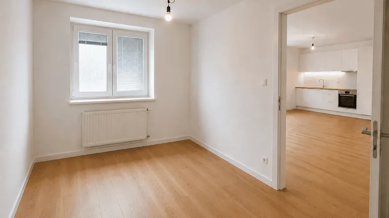Heller Raum mit Holzfußboden, weißen Wänden und Fenster mit Blick in die Küche.