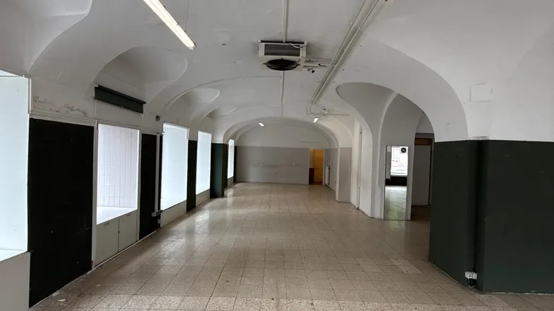 Geräumiger, leerstehender Gewerberaum mit gewölbter Decke und Fliesenboden, bereit für neue Gestaltung.
