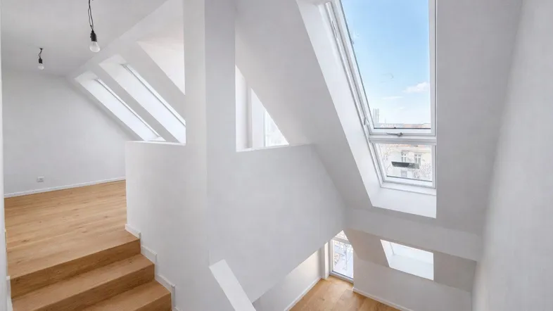 Lichtdurchfluteter Treppenbereich im Dachgeschoss mit großen Dachfenstern und Holztreppe.