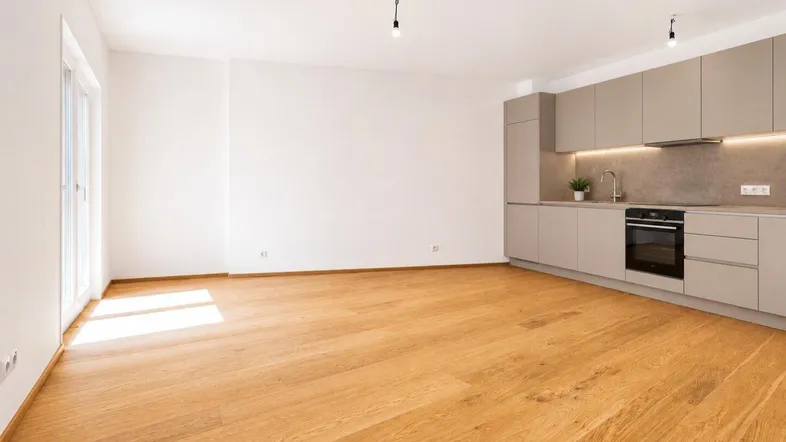 Heller, offener Wohnbereich mit moderner Einbauküche und Zugang zu einem Außenbereich.