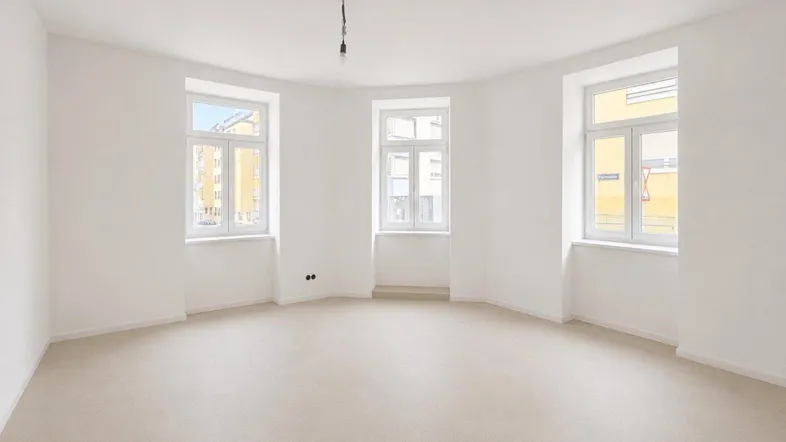 Helles, leeres Zimmer mit drei Fenstern und weiß gestrichenen Wänden, bereit zur individuellen Gestaltung.