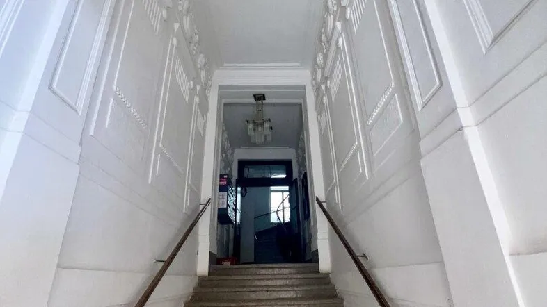 Langer Treppenaufgang mit kunstvollen Stuckverzierungen an den Wänden und einer hohen Decke, die zu einem weiteren Flur führt.