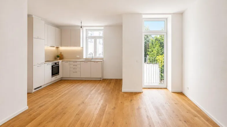 Helle Wohnküche mit moderner Einbauküche, Holzboden und Zugang zu einem französischen Balkon.