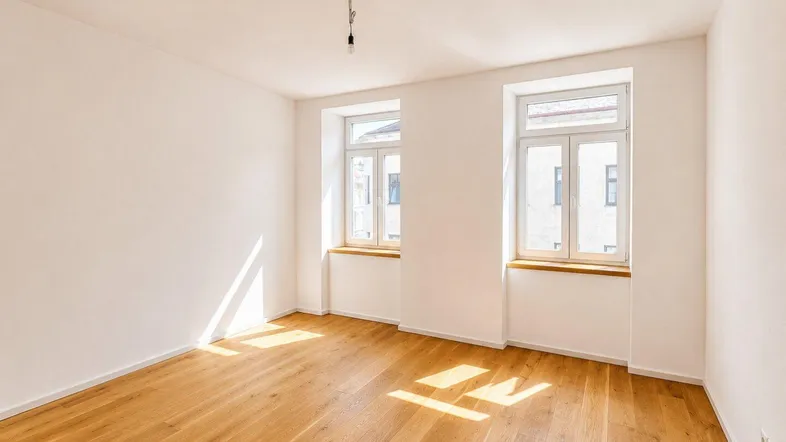 Helles Zimmer mit neuem Parkettboden und zwei großen Fenstern, durch die Sonnenlicht einfällt.