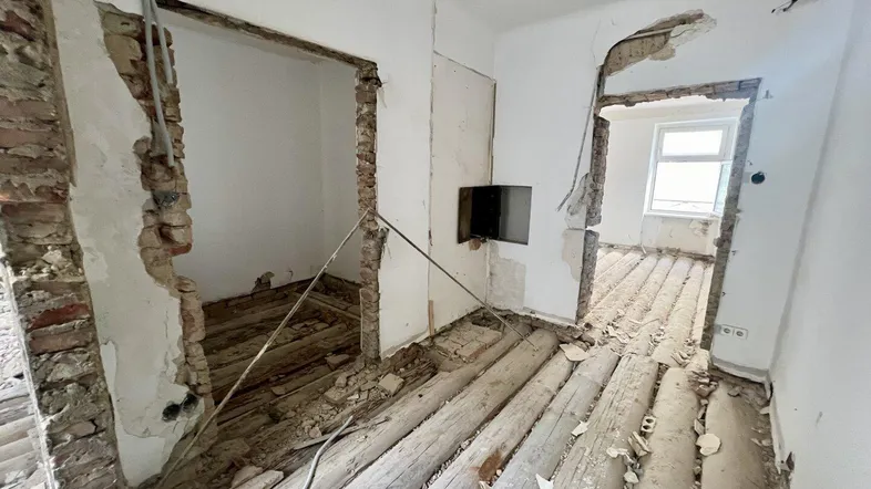 Innenraum in Sanierung mit freigelegten Ziegelwänden und Holzbalken, bereit für den Umbau.