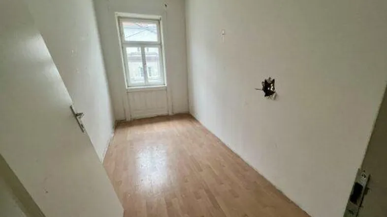 Heller Raum mit Holzboden und einem Fenster, bereit zur individuellen Gestaltung.