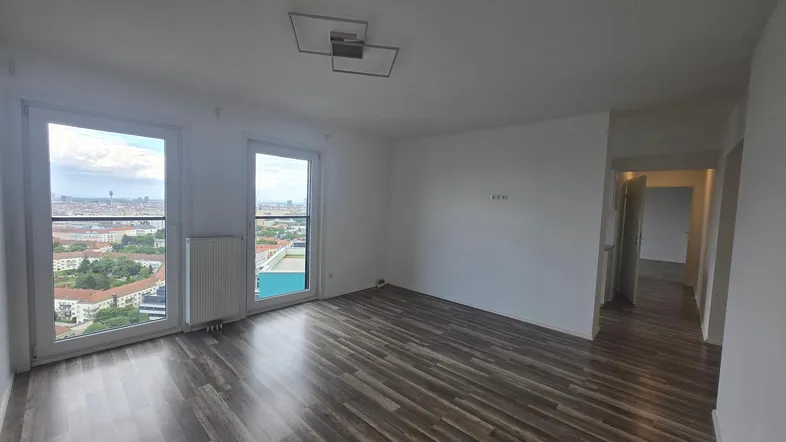 Helles Wohnzimmer mit dunklem Laminatboden und weitem Stadtblick durch große Fenster.