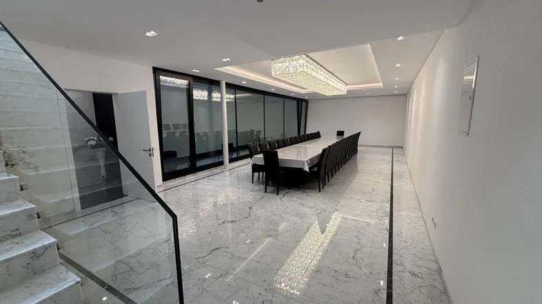 Großer, luxuriöser Speisesaal mit glänzendem Marmorboden, langer Tafel und eleganter Kristallleuchte.