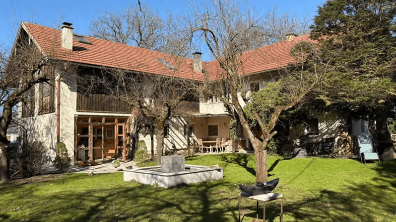 Großes traditionelles Haus mit weitläufigem Garten, altem Baumbestand und einer gemütlichen Außenterrasse.