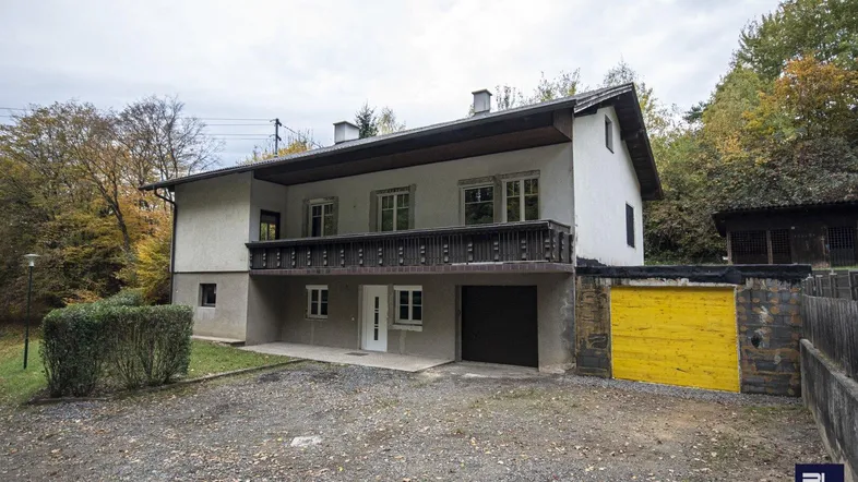 Ansicht des Hauses mit Balkon, Garage und Vorgarten in ländlicher Umgebung.