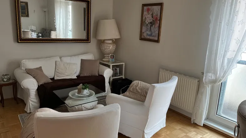Helles Wohnzimmer mit bequemen weißen Sofas, Parkettboden und einem großen Spiegel.