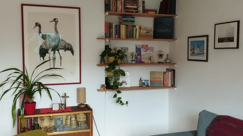 Gemütliches Wohnzimmer mit hellem Parkettboden, bequemer Couch und dekorativen Wandregalen.