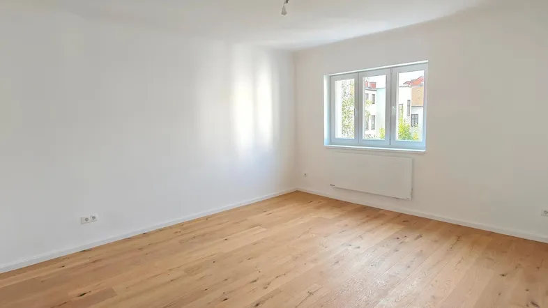 Helles Zimmer mit weiß gestrichenen Wänden und neuem Holzfußboden, ideal als Wohn- oder Schlafzimmer.