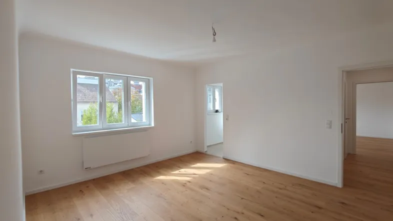 Helles Zimmer mit Holzboden und weißen Wänden, bereit zur individuellen Gestaltung.