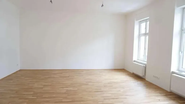 Heller, leerer Raum mit Holzboden und großen Fenstern, bereit zur individuellen Gestaltung.
