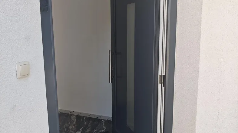 Moderner Eingangsbereich mit dunklem Marmorboden und einer stilvollen Eingangstür.