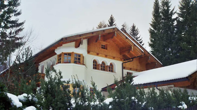 Traditionelles Haus mit Holzelementen, schneebedecktem Dach und alpiner Architektur.