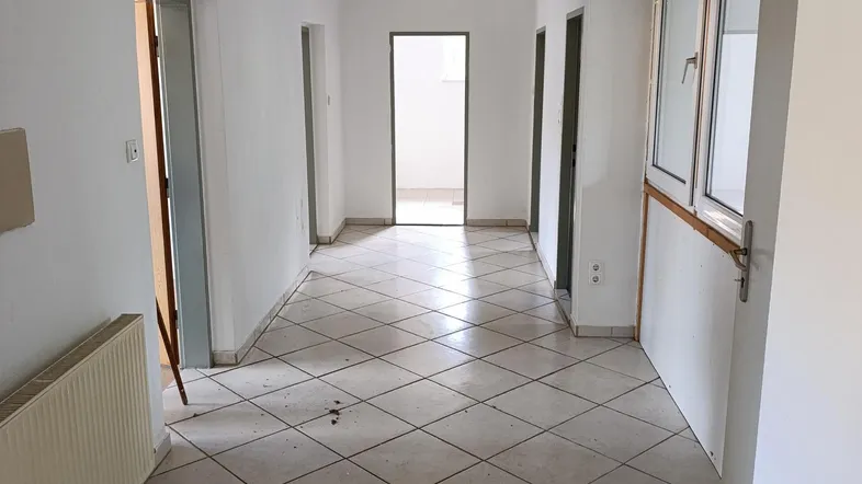 Heller Flur mit Fliesenboden und Zugang zu mehreren Zimmern, bereit für Renovierung.