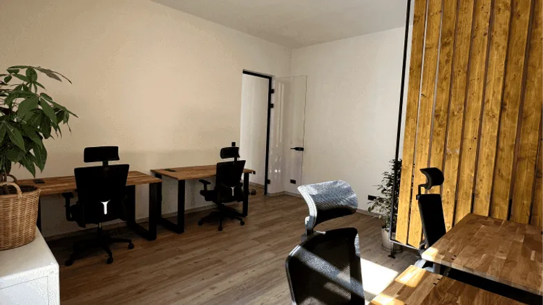 Heller Büroraum mit modernen Holzschreibtischen, ergonomischen Stühlen und natürlichem Lichteinfall.