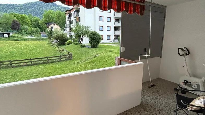 Geräumiger Balkon mit Markise, Blick ins Grüne und auf die umliegende Berglandschaft.