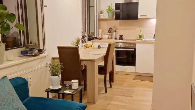 Offener Wohn- und Essbereich mit integrierter Küche, Holzboden und einem gemütlichen Sofa.