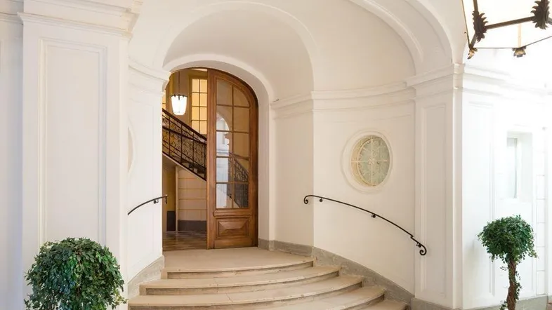 Elegante Eingangshalle mit geschwungener Treppe, hohen Decken und klassischer Beleuchtung.