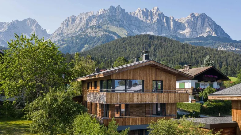 Modernes Holzhaus mit traditioneller Architektur und beeindruckendem Bergblick in alpiner Umgebung.
