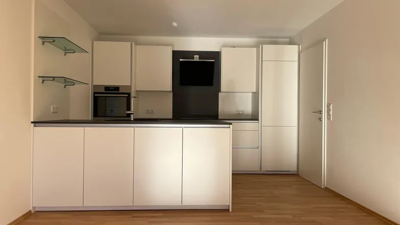 Moderne Einbauküche in Weiß mit dunkler Arbeitsplatte und integrierten Geräten.