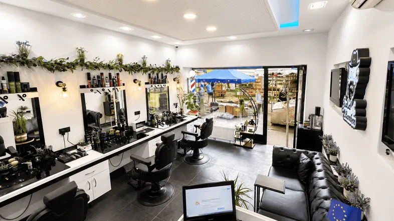 Heller und moderner Friseursalon mit mehreren Bedienplätzen, bequemen Ledersofas und Blick nach draußen.