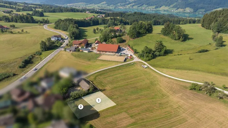 Luftaufnahme eines Grundstücks in ländlicher Umgebung mit See- und Bergblick, ideal für den Bau.