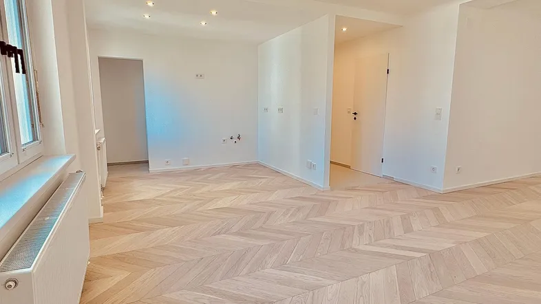Geräumiges, helles Wohnzimmer mit Fischgrätparkett und Einbaustrahlern in der Decke.