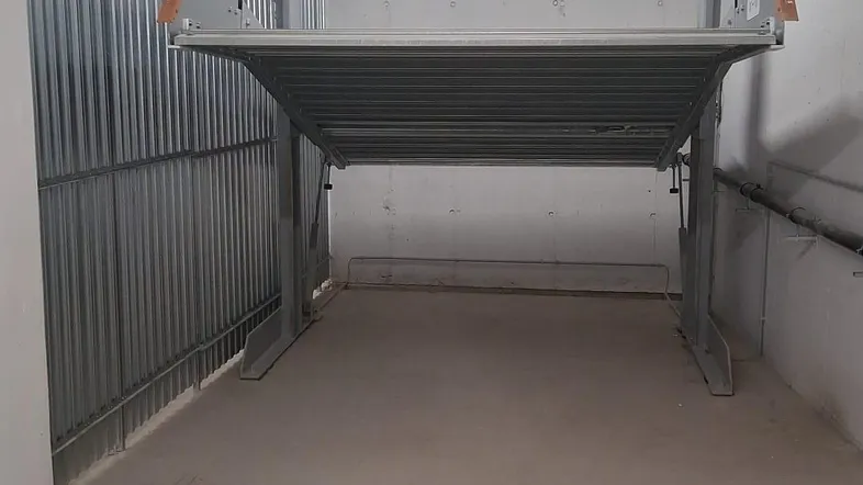 Tiefgaragenstellplatz mit einem mechanischen Parksystem für zwei Fahrzeuge in einem gepflegten Zustand.
