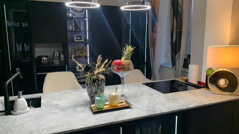 Moderne Küche mit großer Kücheninsel, Induktionskochfeld und eleganten schwarzen Schränken.
