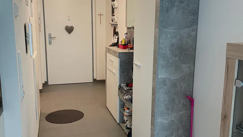 Heller Eingangsbereich mit Fliesenboden, Garderobenschrank und dekorativem Kronleuchter.