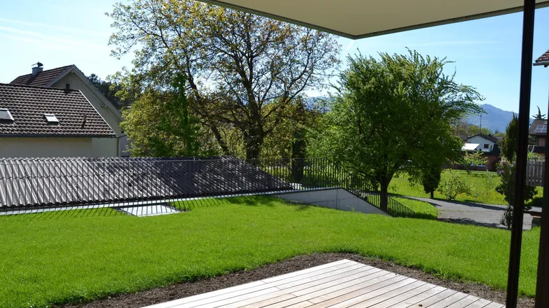 Große Holzterrasse mit angrenzendem Rasen und Blick auf die umliegende grüne Landschaft.