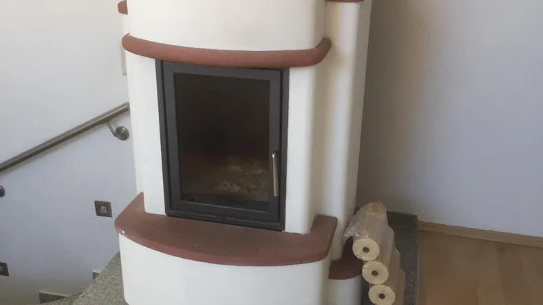 Kaminofen mit Holzscheiten und Treppenaufgang in einem hellen Wohnbereich.